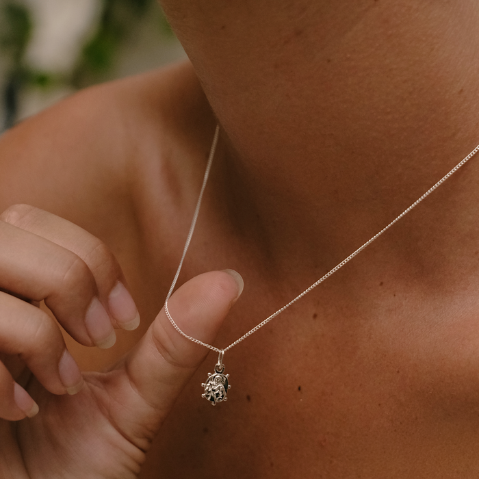 Close-up of a person wearing a silver necklace with a pendant.