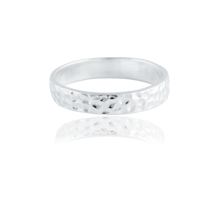 A single narrow, gold hammered ring isolated on a white background with a reflection.