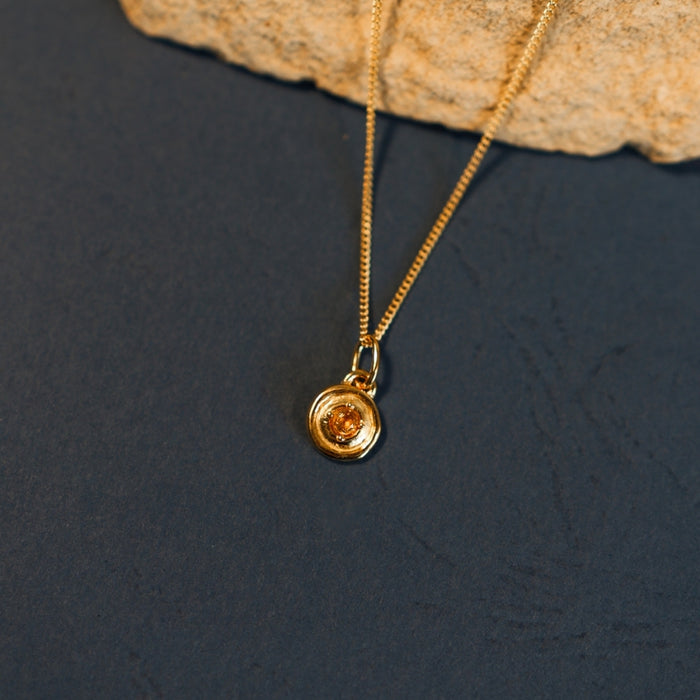 Gold necklace with a pendant on a dark surface