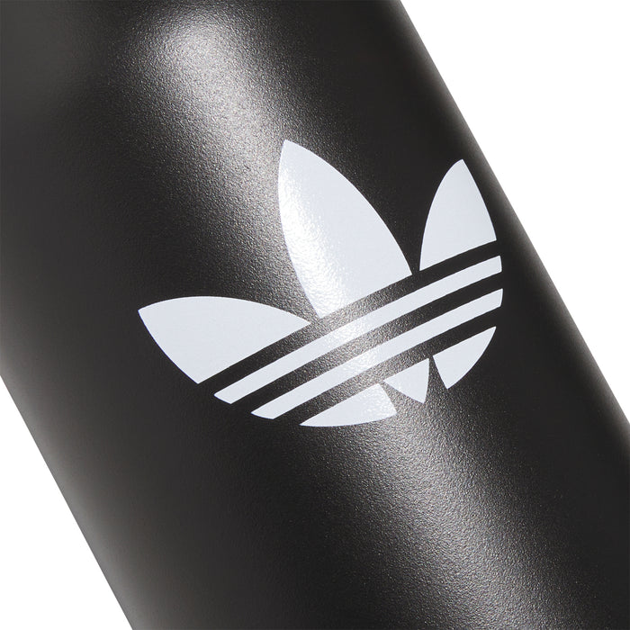Matte black bottle with large white trefoil and stripes logo, close-up