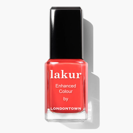 A bottle of Piccadilly Square nail polish by LONDONTOWN, featuring an ultra-bright blood orange crème color with a black cap, on a white background. This vegan and cruelty-free nail polish delivers both style and conscience.