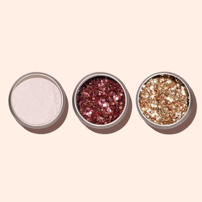 Three small round Manucurist containers—one with Pink Quartz Biodegradable Glitter, one with chunky rose gold glitter, and one with chunky gold glitter—sit on a beige background, ideal for creative nail art looks.