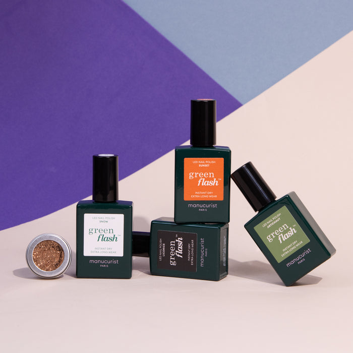 Four bottles of Pumpkin Patch gel polish by Manucurist are arranged with a small open pot of copper glitter, all set against a geometric purple, blue, and cream background.