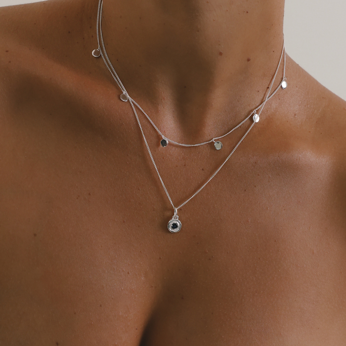 Necklace with pendant on a person's neck against a neutral background