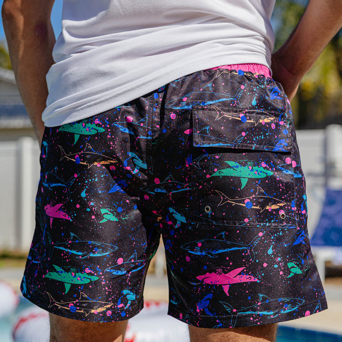 Rear close-up of BL101 neon shark swim shorts on a male model, showing the back pocket with grommet drain.