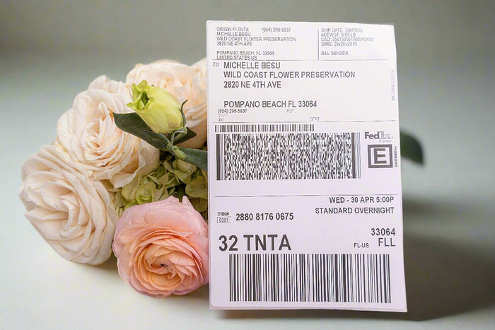 FedEx Priority Overnight shipping label in front of a pink rose arrangement for flower preservation shipping