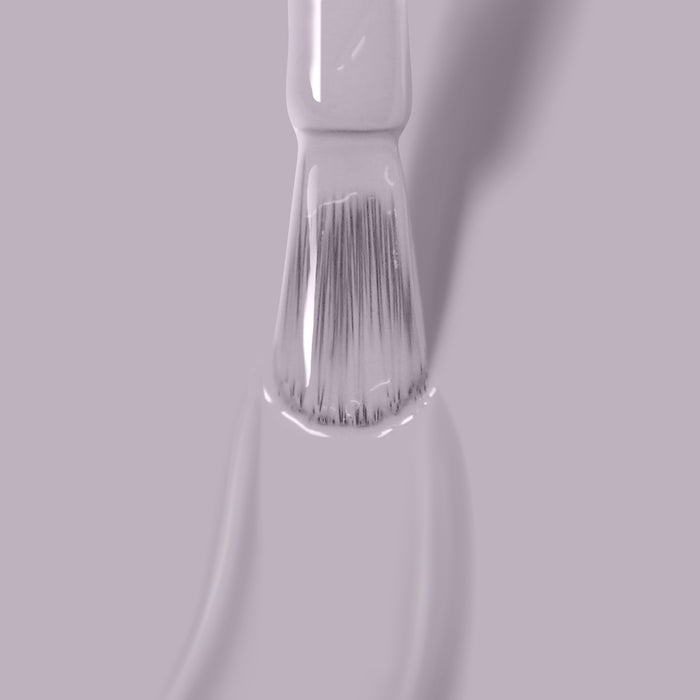 Close-up of a brush with Silver Birch vegan nail polish by LONDONTOWN on its bristles, against a light pink background.