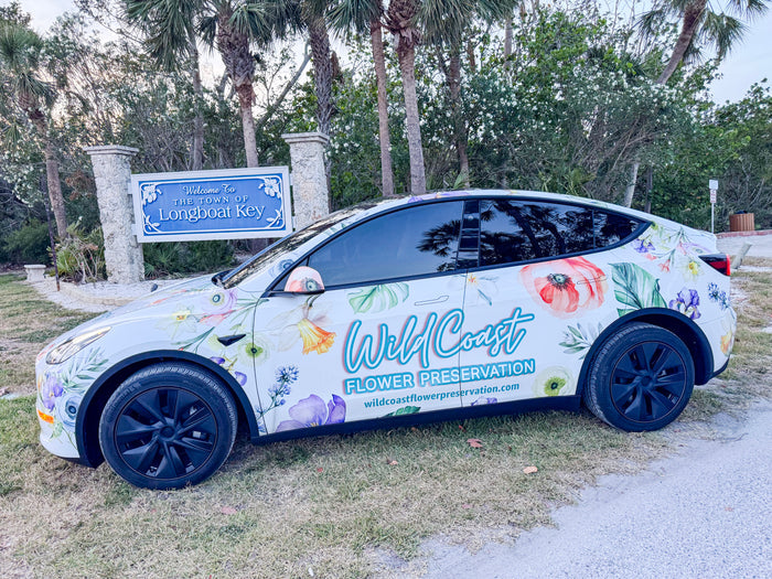 Car with floral design and 'Wild Coast Flower Preservation' branding parked in front of West Coast of Florida  Wedding Venue, Longboat Key Bouquet Preservation  Pickup Service