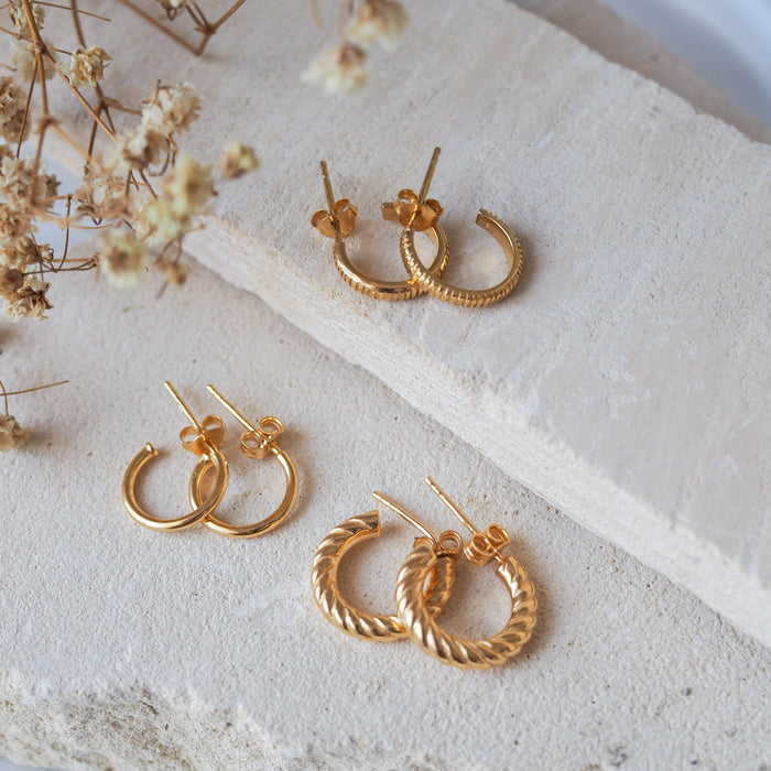 hoops earrings gold displayed on white stone with dried flowers