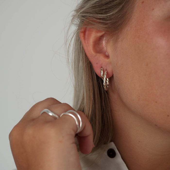 a woman with blonde hair wearing hoops earrings silver and ring silver