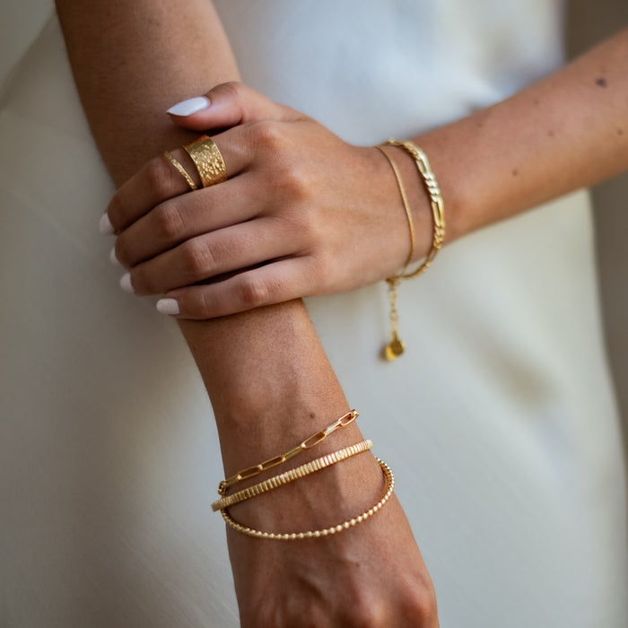 a woman with her white dress wearing  a multiple bracelets gold on her wrist and ring gold on her finger