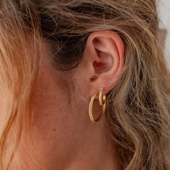 The MET Stripe Thin Earrings gold on woman with blonde hairs