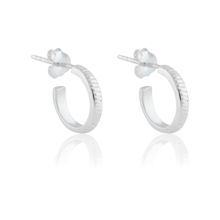a pair of  silver thin hoops earrings on white background and a reflection on it