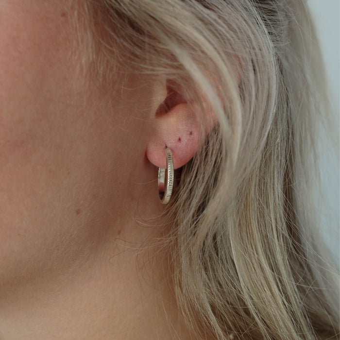 a woman with blonde hair wearing a piece of silver earrings on her