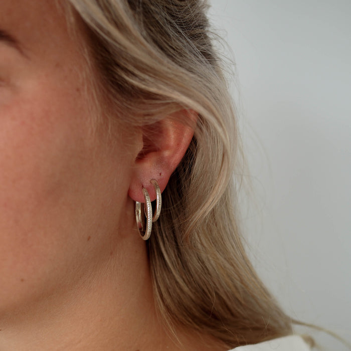 a woman wearing two pieces hoops earrings silver on her