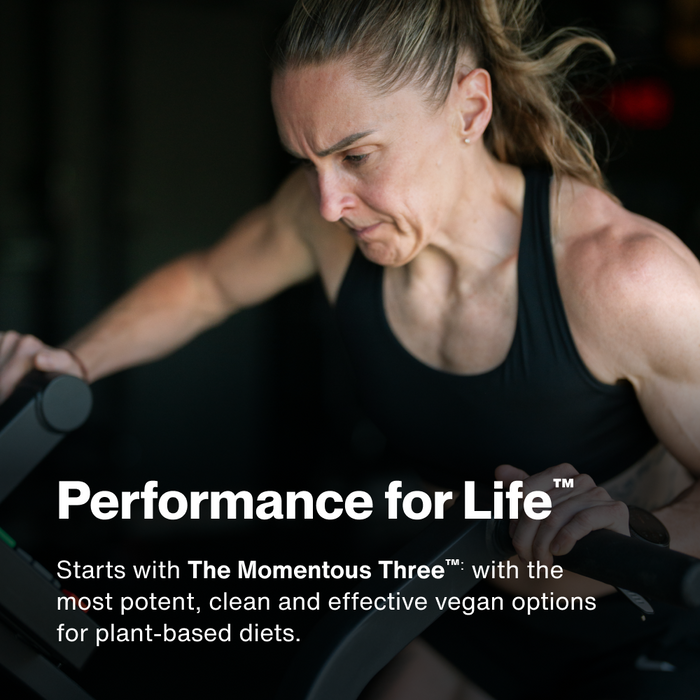 Woman in black tank top exercising with dumbbells against dark background.
