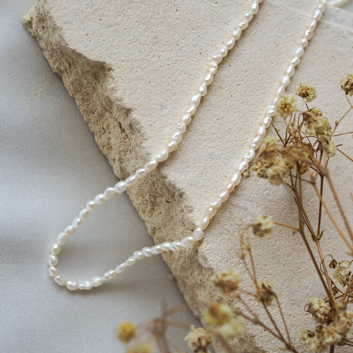 Timeless Mini Pearl Necklace - Silver displayed on beige stone