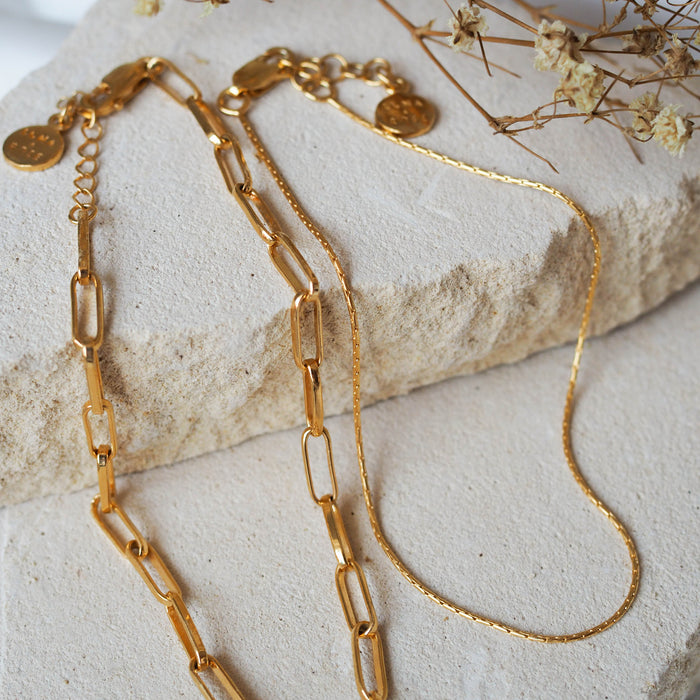 two pieces anklets gold displayed on beige stone