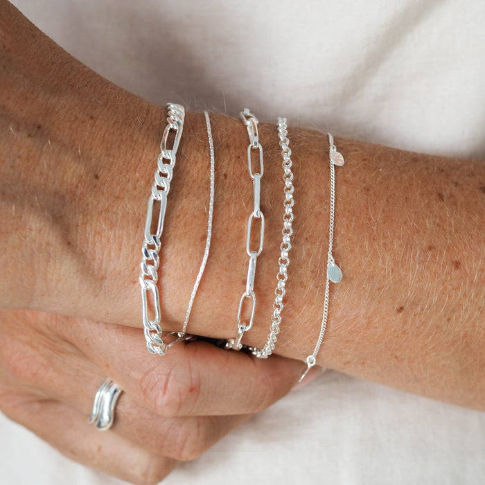a woman with white dress wearing multiple bracelets silver and ring silver